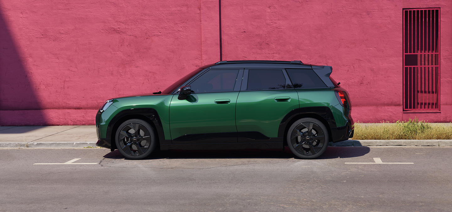Side view of the all-electric MINI Aceman in British Racing Green and Black Roof. on a street.