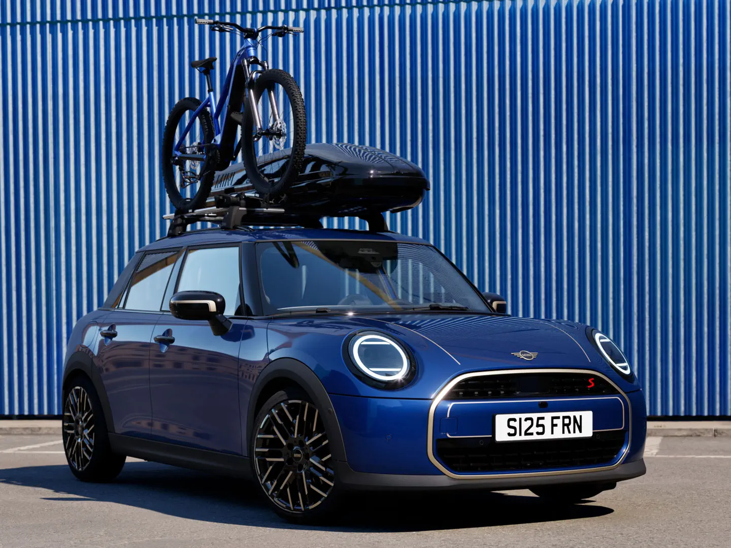 Front view of MINI Aceman in Indigo Sunset Blue with MINI Roof Bike Rack, carrying a mountain bike and MINI Roof Box 320.