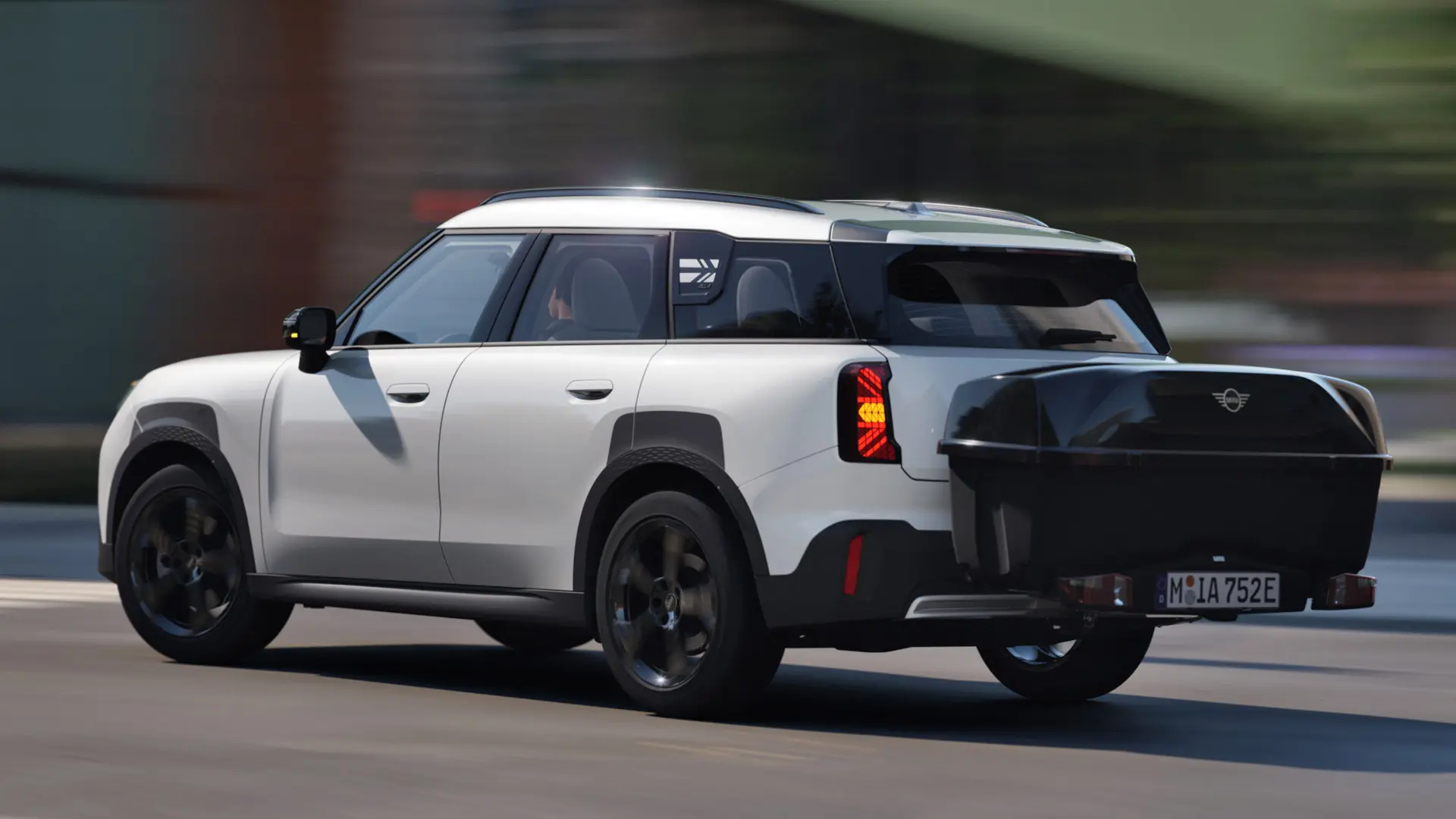 Rear side view of MINI Aceman in Nanuq White equipped with a MINI Rear Bike Rack and carrying the MINI Rear Box. 