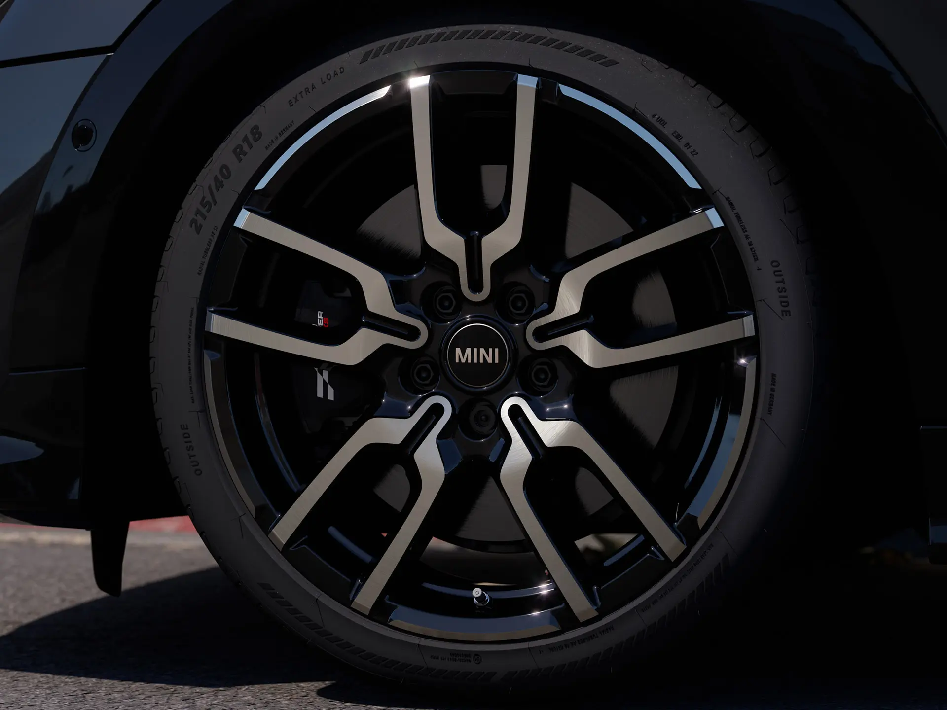 Close-up of the JCW Lap Spoke alloy wheel showing its distinctive open spoke design structure in Jet Black finish. 