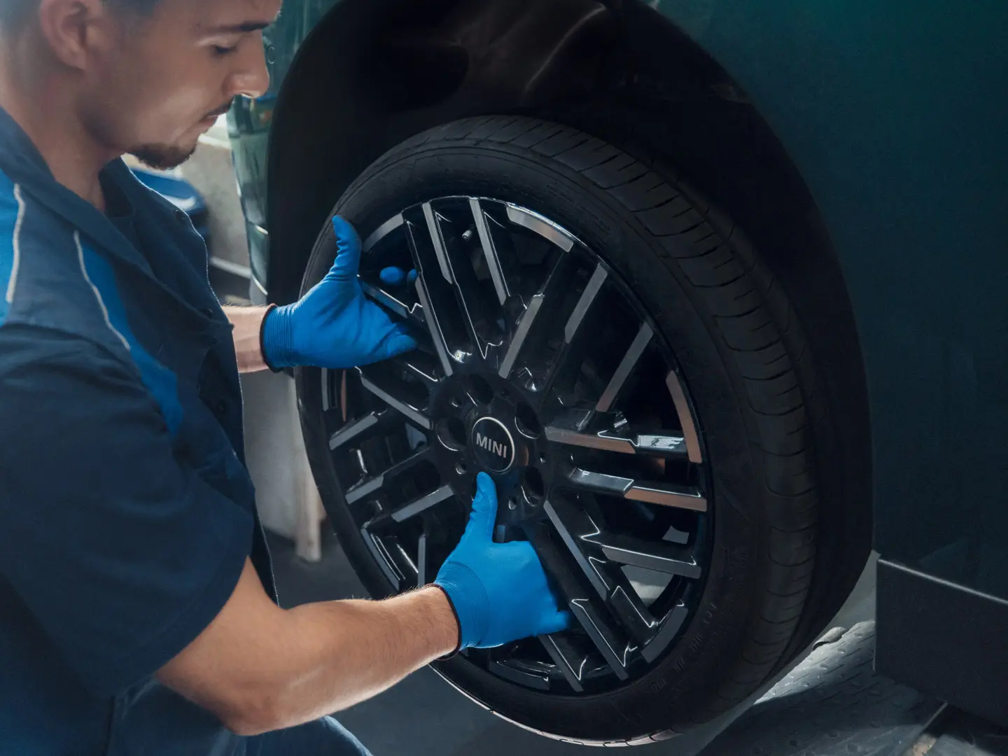 A MINI service technician installs a MINI 18" Night Flash Spoke Bicolour Light Alloy Wheel onto a MINI Cooper Electric.